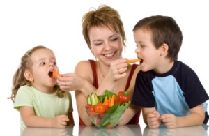 Woman feeding kids with vegetables